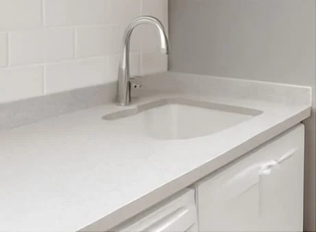 White kitchen sink with a faucet and cabinet below, in a minimalistic kitchen with white subway tile backsplash.