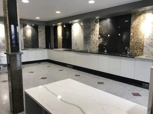 Modern kitchen with white cabinets, marble backsplash, and a large marble countertop island in the center.
