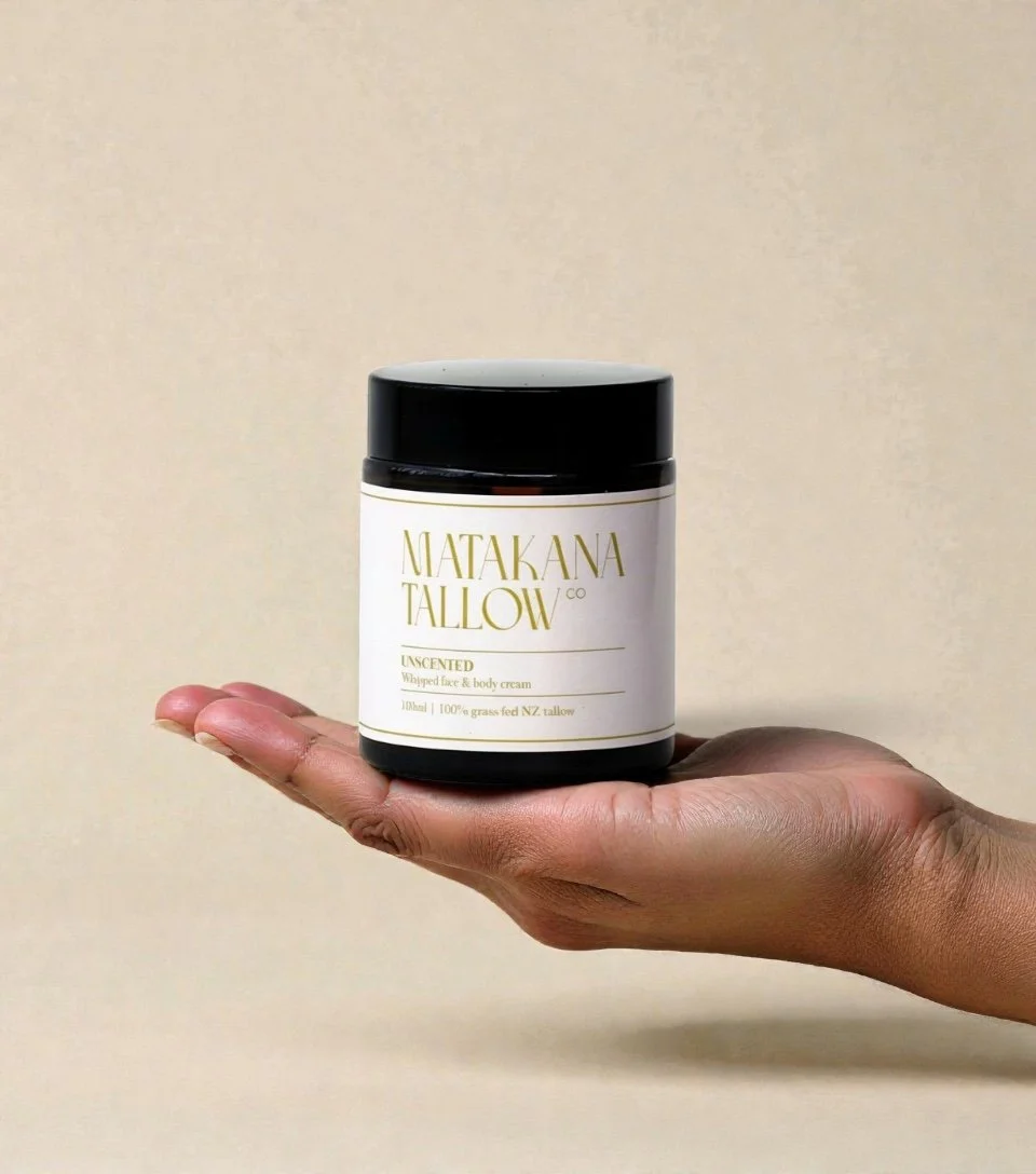 A hand holding a jar of Matakana Tallow scented whipped face and body cream.