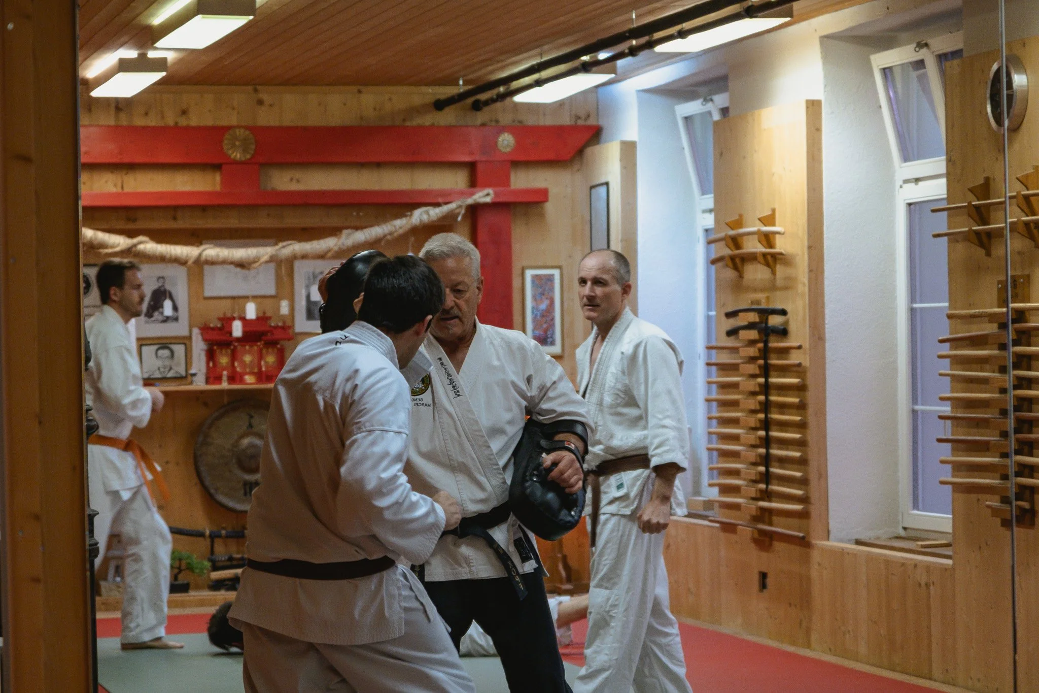Menschen in weissen Dōgi, die in einem Dojo Pratzentraining trainieren.