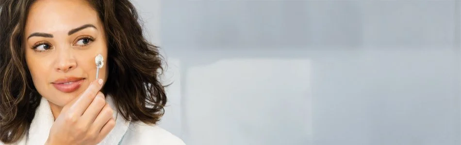 A woman holding a cotton swab near her face, preparing to apply or remove skincare or makeup.