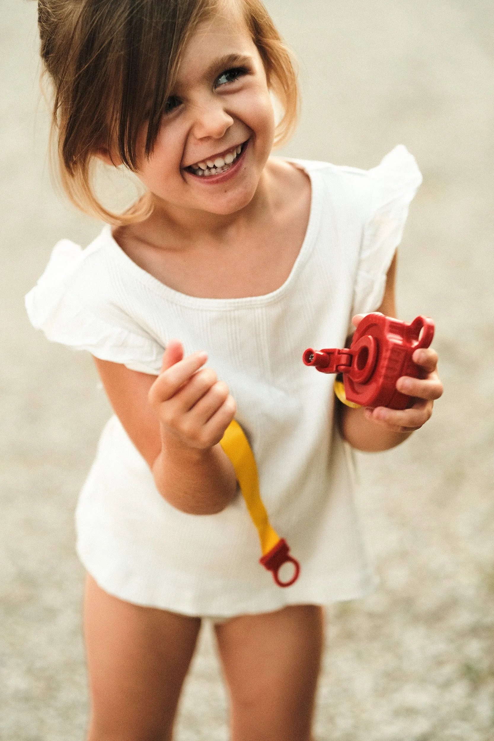 Portrait jeune enfant souriante tenant un jouet, image spontanée et pleine de vie — Guillaume Auray-Runel photographe enfants Normandie