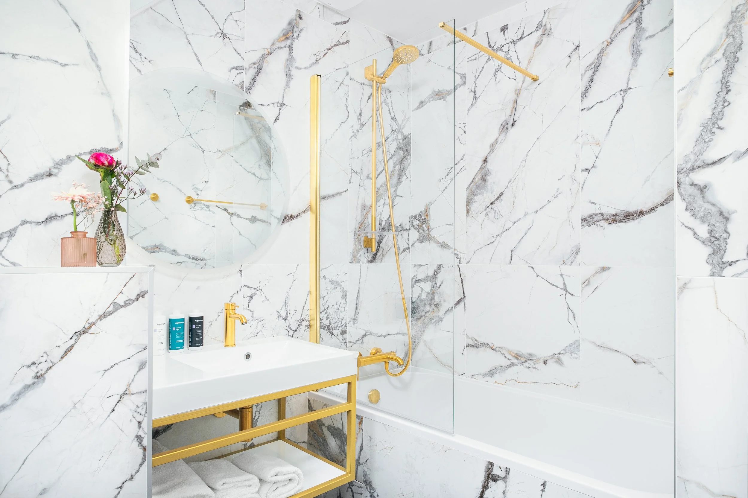 Salle de bain moderne en marbre blanc nervuré avec baignoire et robinetterie dorée à l'Hôtel Best Western Plus Le Moderne situé à Caen centre-ville.