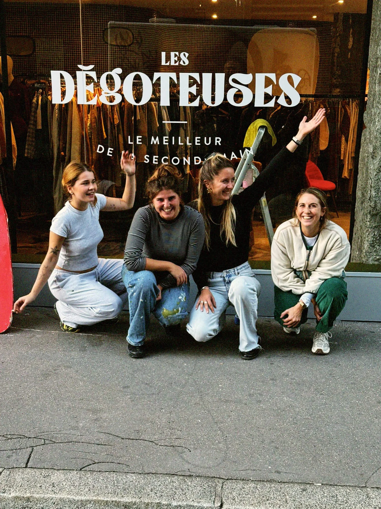 Groupe "les Dégoteuses" de quatre femmes souriantes et souriantes, posant devant une vitrine de magasin de vêtements