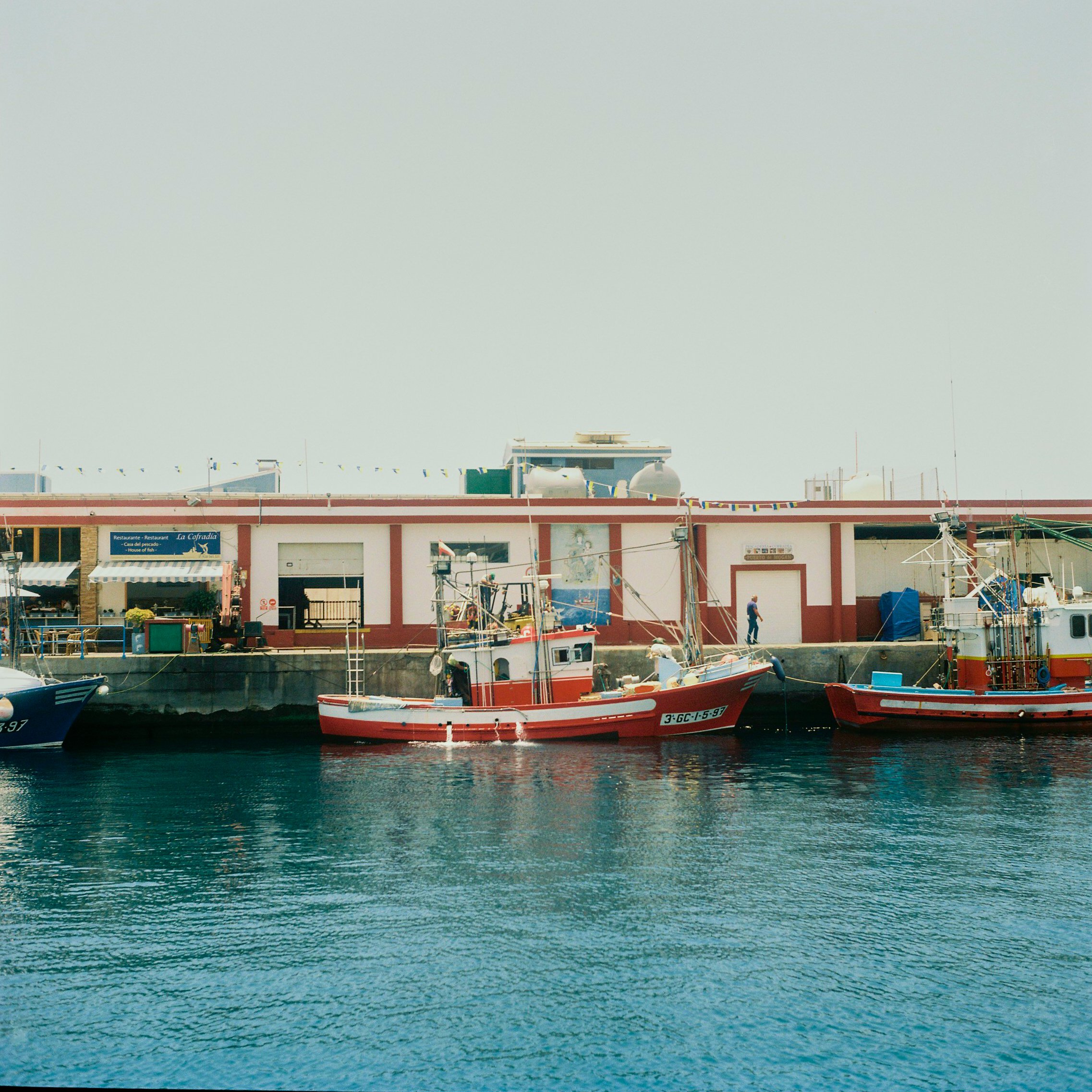 Boats docked at a harbor with a building in the background.
