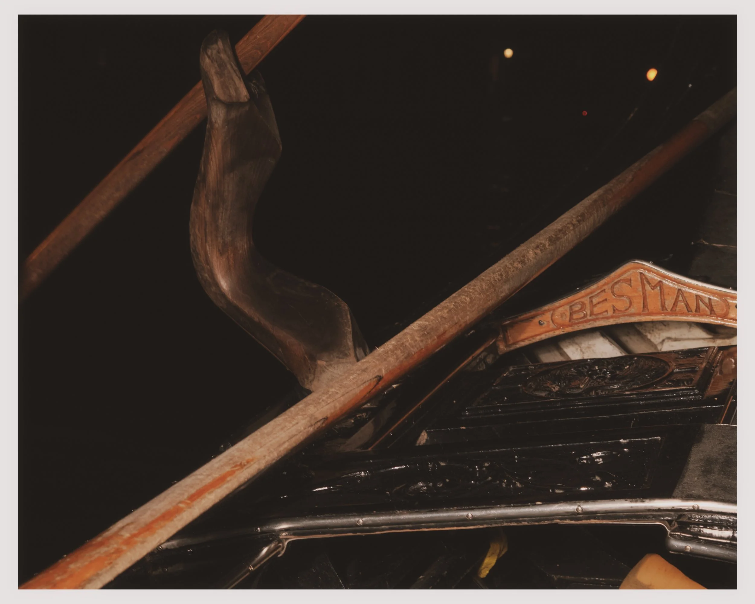 A vintage wooden hand saw with the label 'BES MAN' carved into it, resting on an assortment of wood and metal objects.