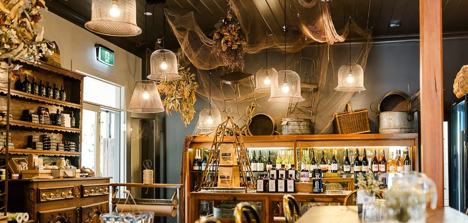 Interior of a the Stanley Pub Store decorated with hanging lamps, dried flowers, and vintage items on wooden shelves and display cases.