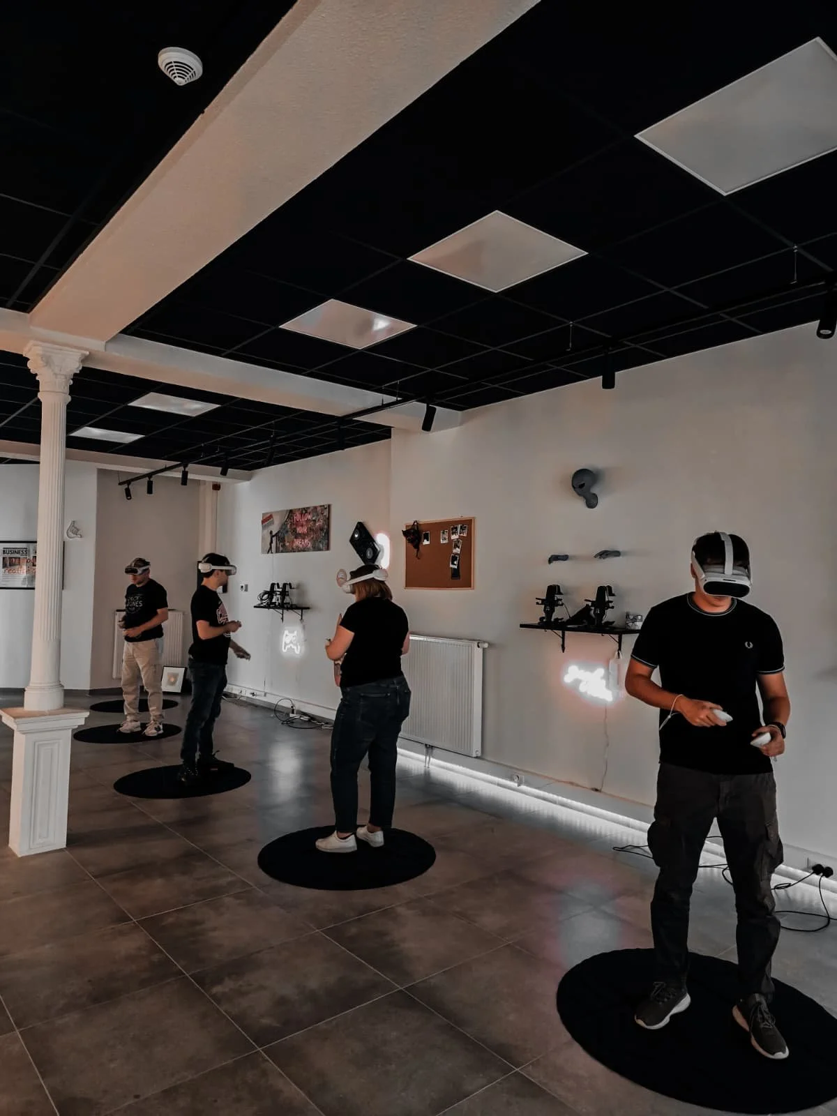 Groupe de personnes utilisant des casques de réalité virtuelle dans une pièce avec murs blancs et décorations modernes.