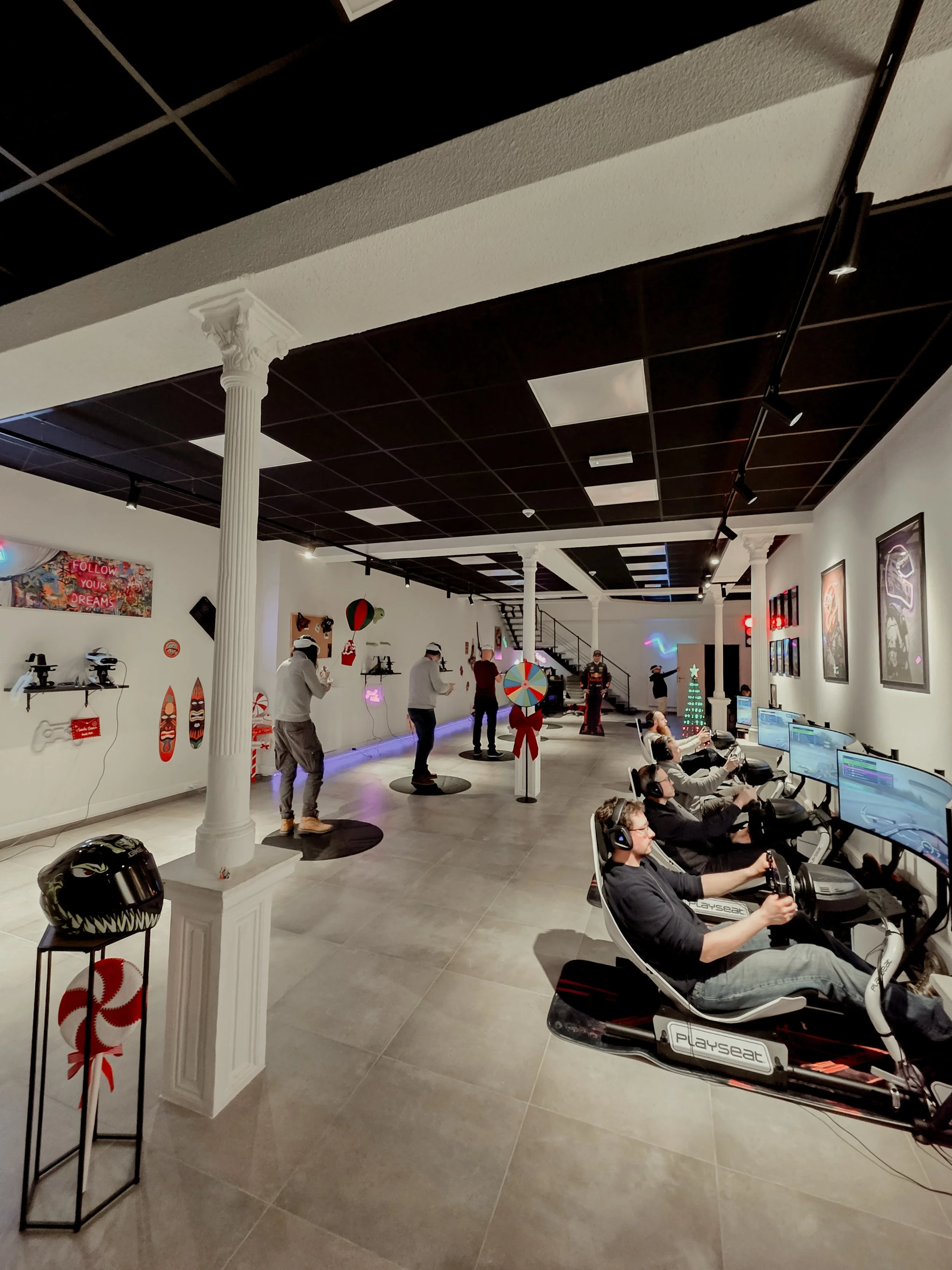 Salle de jeux avec plusieurs personnes utilisant des simulateurs de course, décorée avec des motifs de Noël et des décorations festives