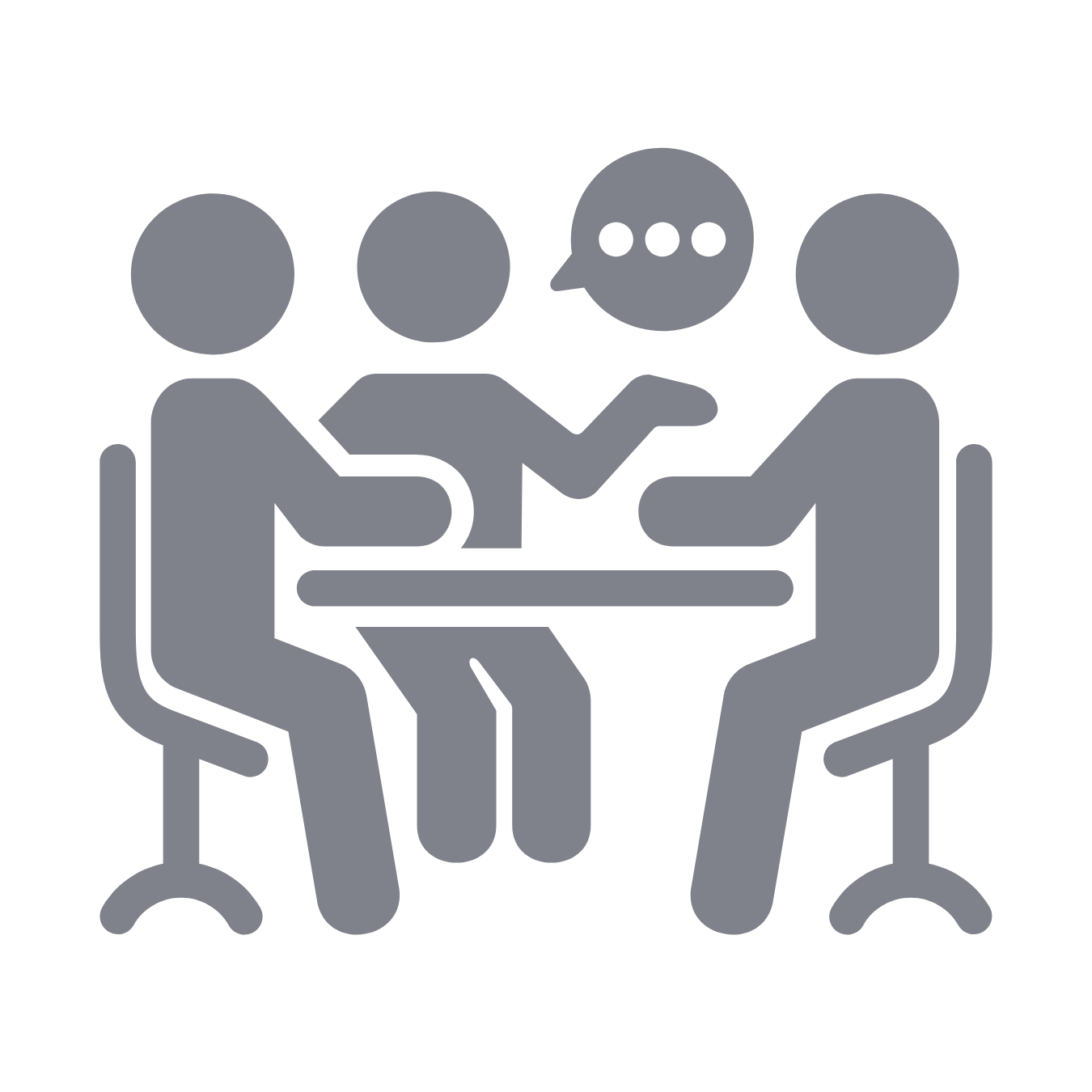 An icon to represent in-person learning. Three people sitting around a table having a discussion, with a speech bubble indicating conversation.