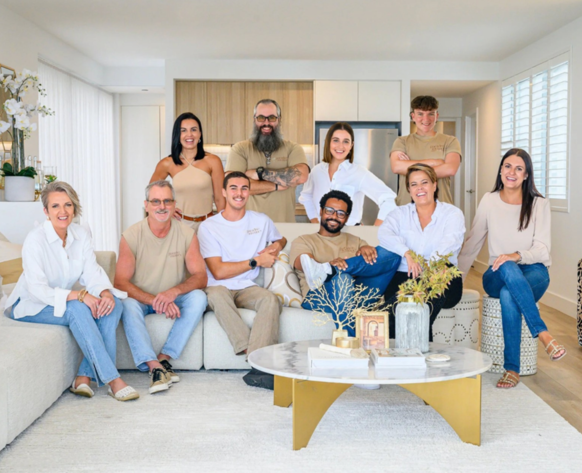 A group of ten diverse people smiling in a living room with modern decor.