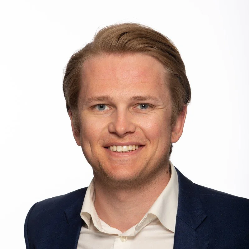 Headshot of a smiling man with blond hair, wearing a navy blazer and white shirt, against a white background. Andreas Gran-Halvorsen.