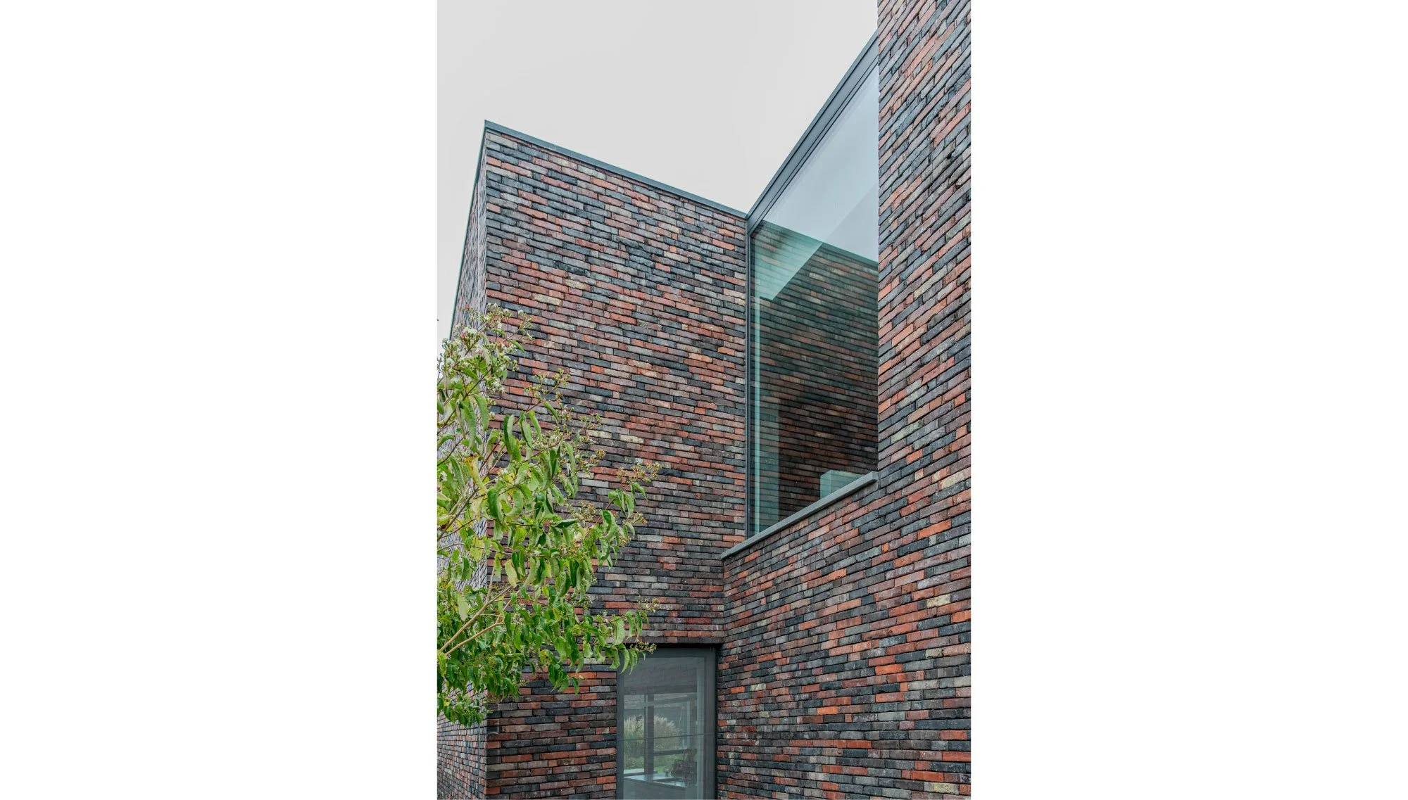 Modern gebouw bakstenen en een grote glazen venster, getekend door Gert Anthonissen Architect. Noord Antwerpen, nieuwbouw, plan.