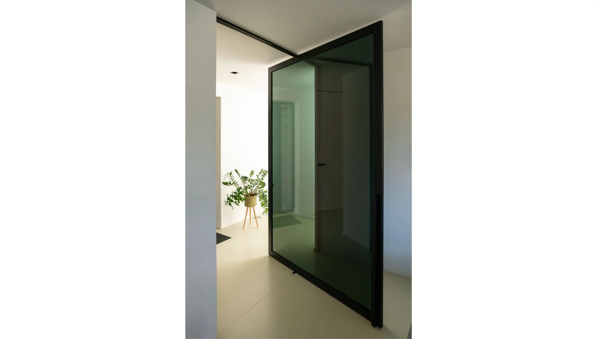Moderne glazen deur met zwarte frame in een wit interieur, ontworpen door Gert Anthonissen Architect.