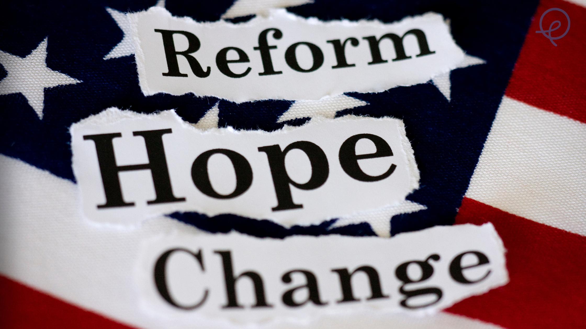Tear-ed paper messages that read "Reform," "Hope," and "Change" placed on a fabric with a pattern of the American flag.