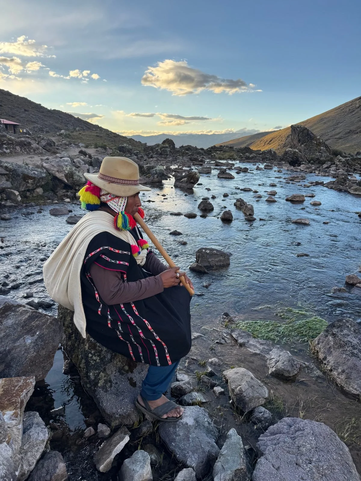 “Andean maestro beside a mountain river during an Earth Wisdom retreat in Peru”