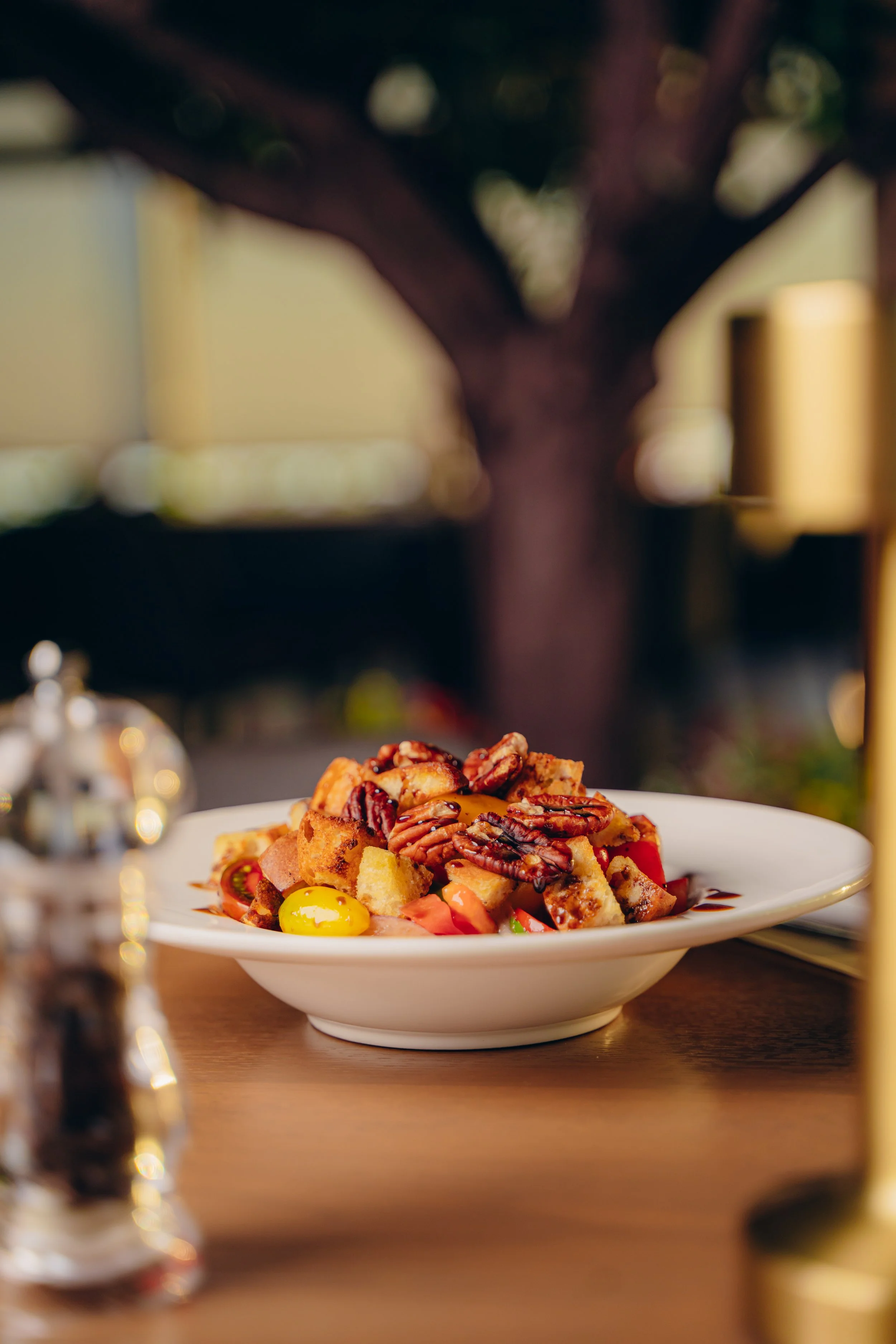 A plate of assorted desserts, including cake pieces, nuts, and yellow candies, on a wooden table with blurred background.