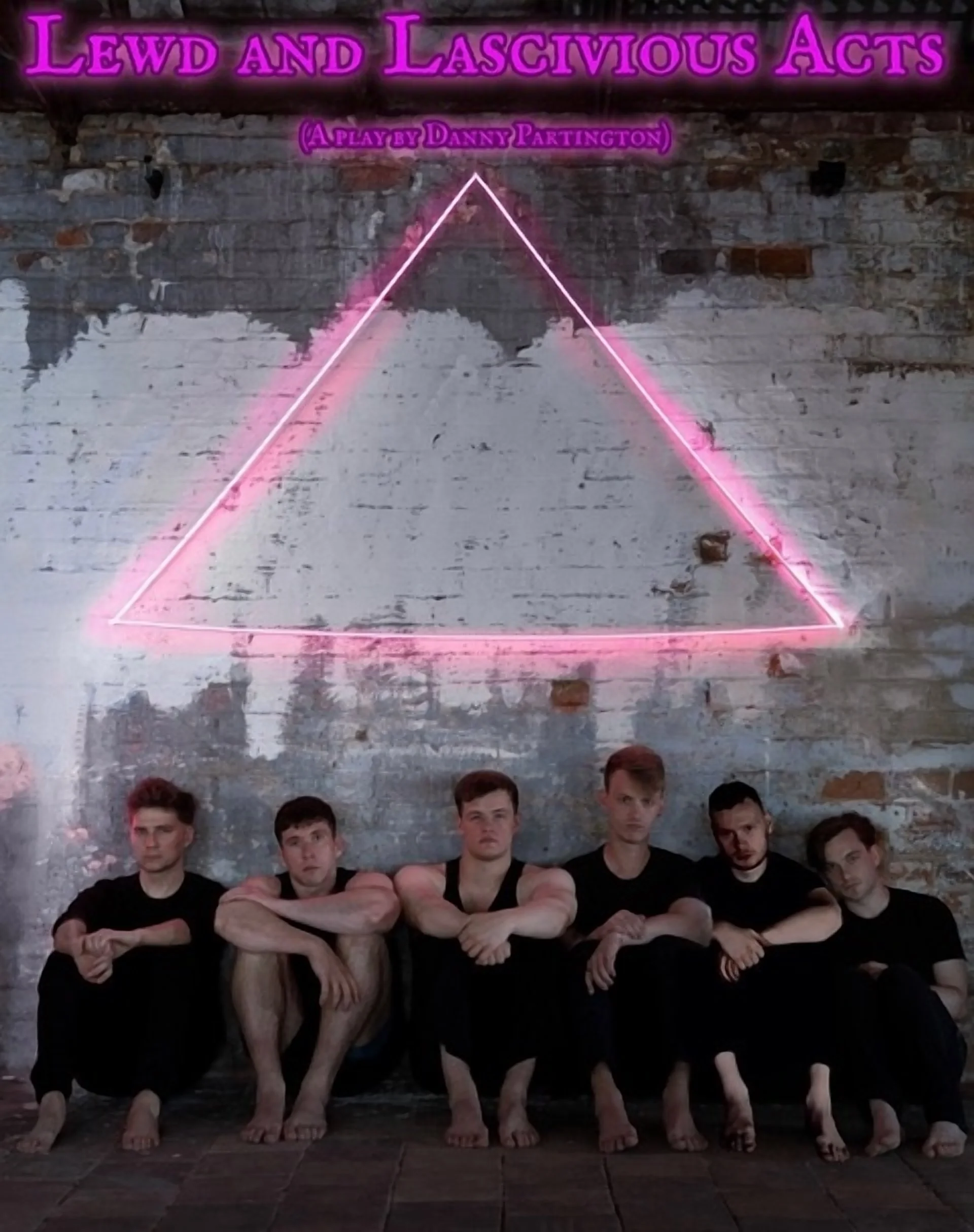 A group of six young men sitting on the floor against a wall with exposed brick and peeling paint. Above them, a pink neon triangle outline and purple neon text that reads 'Lewd and Lascivious Acts' with smaller purple text underneath belonging to 'A Play by Danny Partington'.
