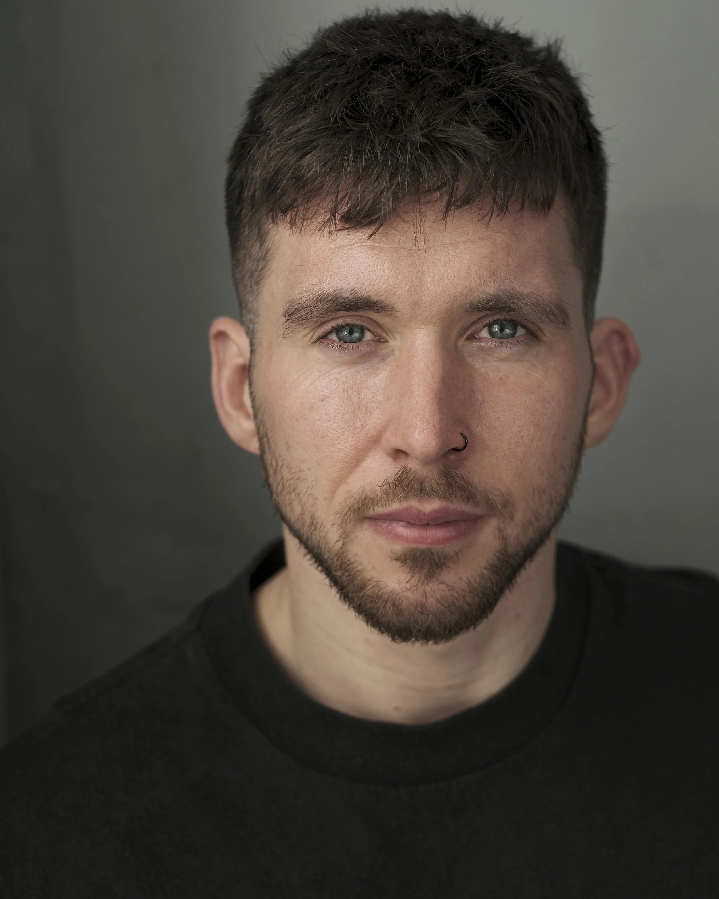 Young man with short brown hair smiling, standing in front of metallic streamers.