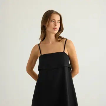 Model wearing black A-line mini dress side angle.png