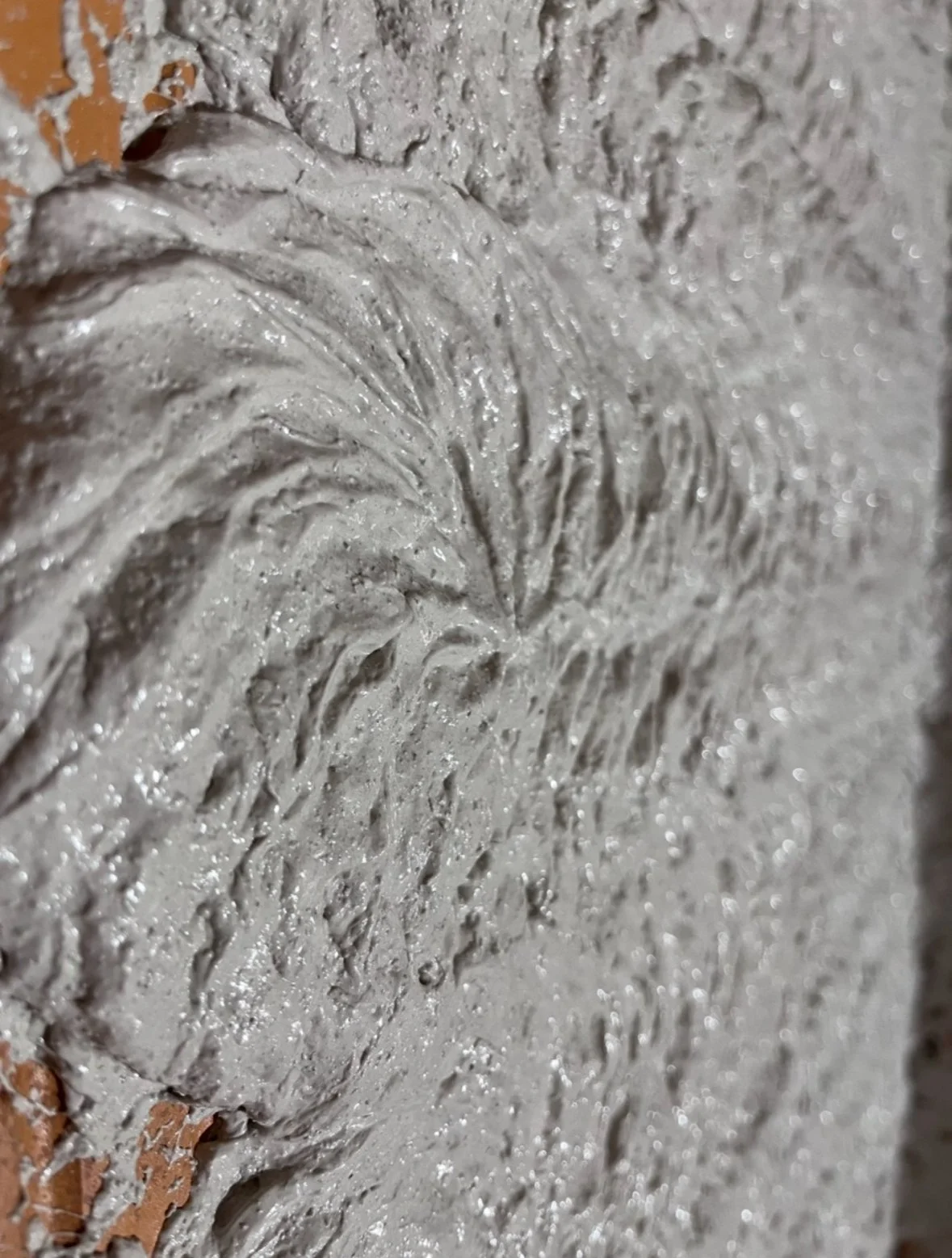 Detailaufnahme einer Wand mit eingraviertem Muster, überwiegend in Grau gehalten.