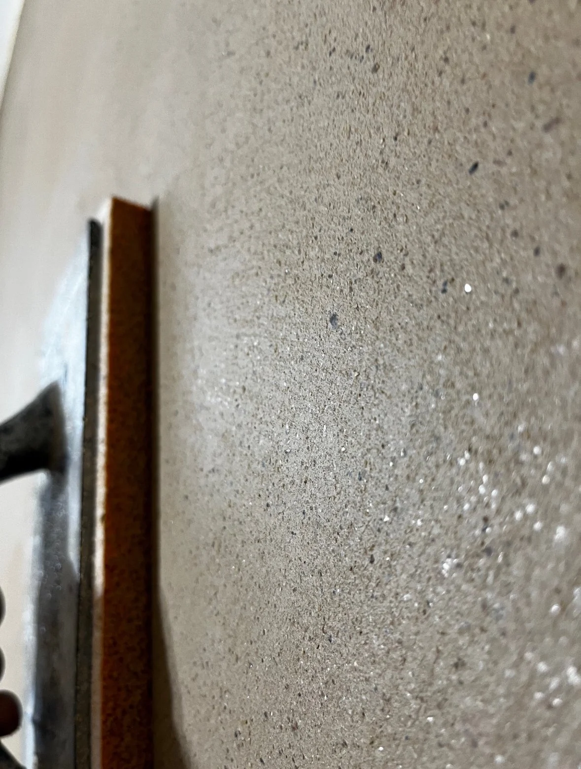 Ein Handrasierer liegt auf einer Sandoberfläche, die Oberfläche ist glatt mit kleinen Glitzerpartikeln.