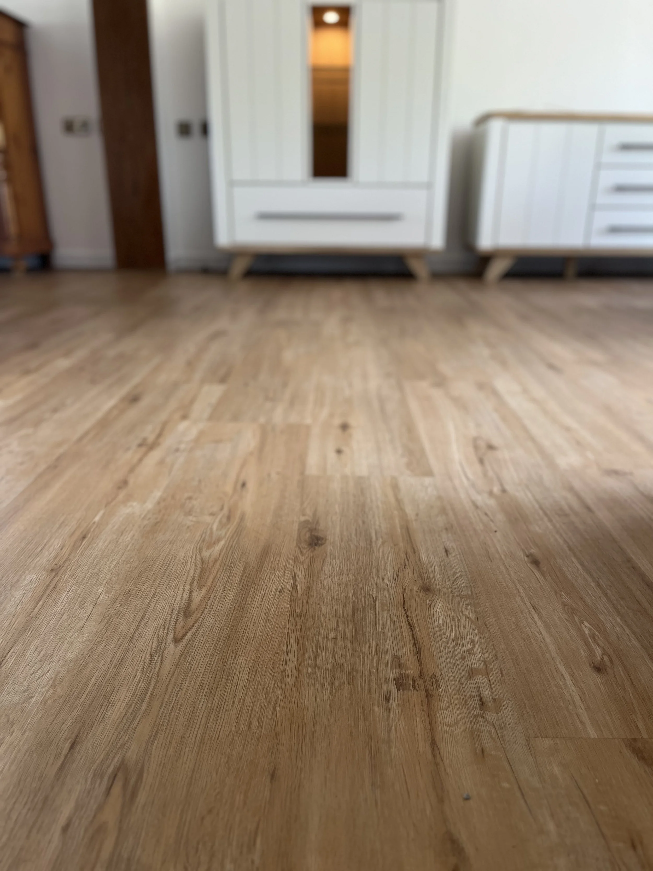 Nahaufnahme eines Holzbodenbodens mit Möbel im Hintergrund.