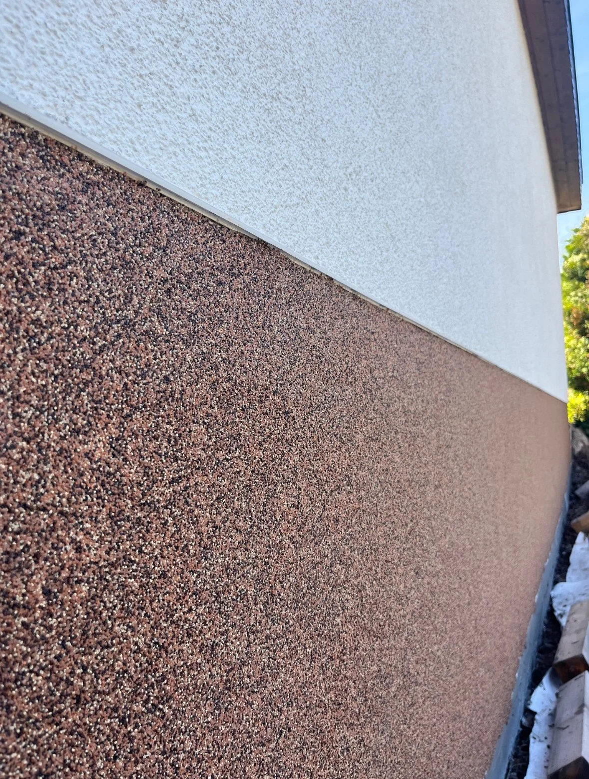 Nahaufnahme einer Außenwand mit weißer Putzschicht und roter Sandkastentextur