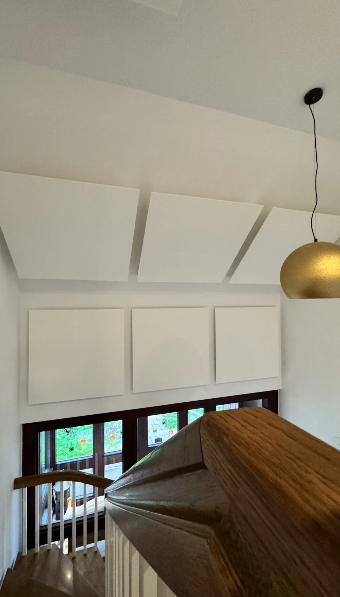 Innenaufnahme einer Treppe mit Holzbalken, weißen Wandpaneelen und einer Deckenlampe.