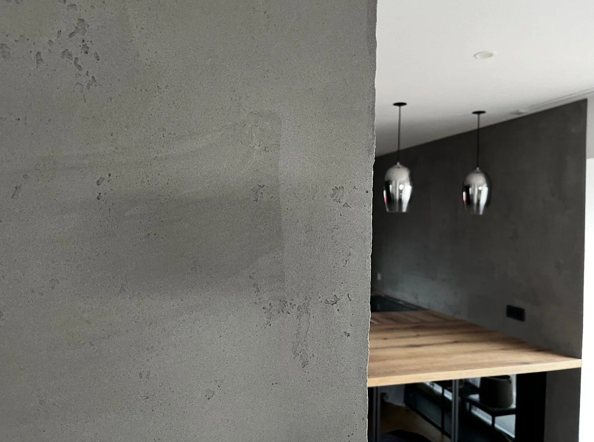 Teil einer modernen Küche mit dunklen Wänden, zwei hängenden Silberlampen und einer Holzarbeitsplatte.