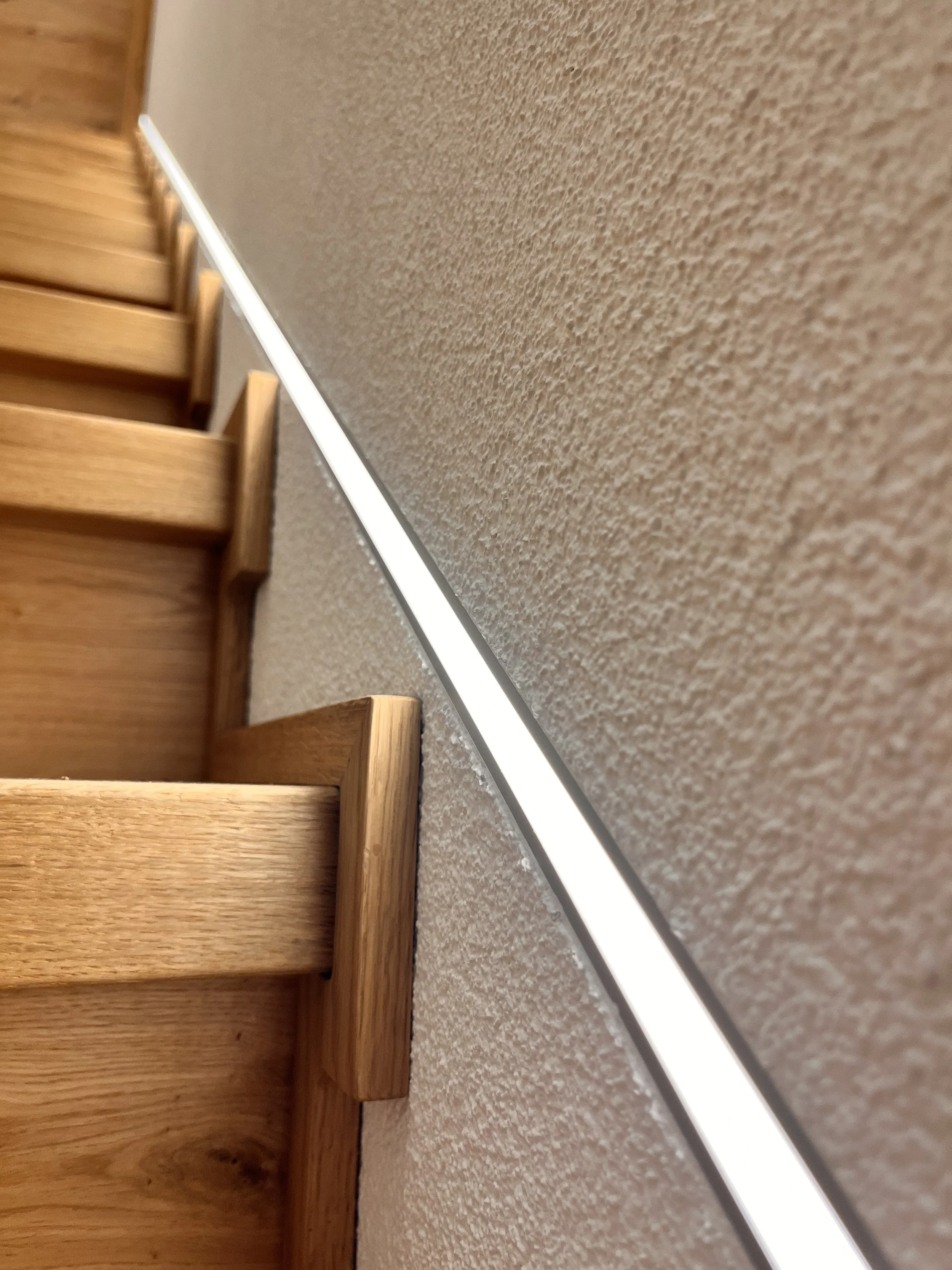 Holztreppen mit LED-Leiste an der Wand