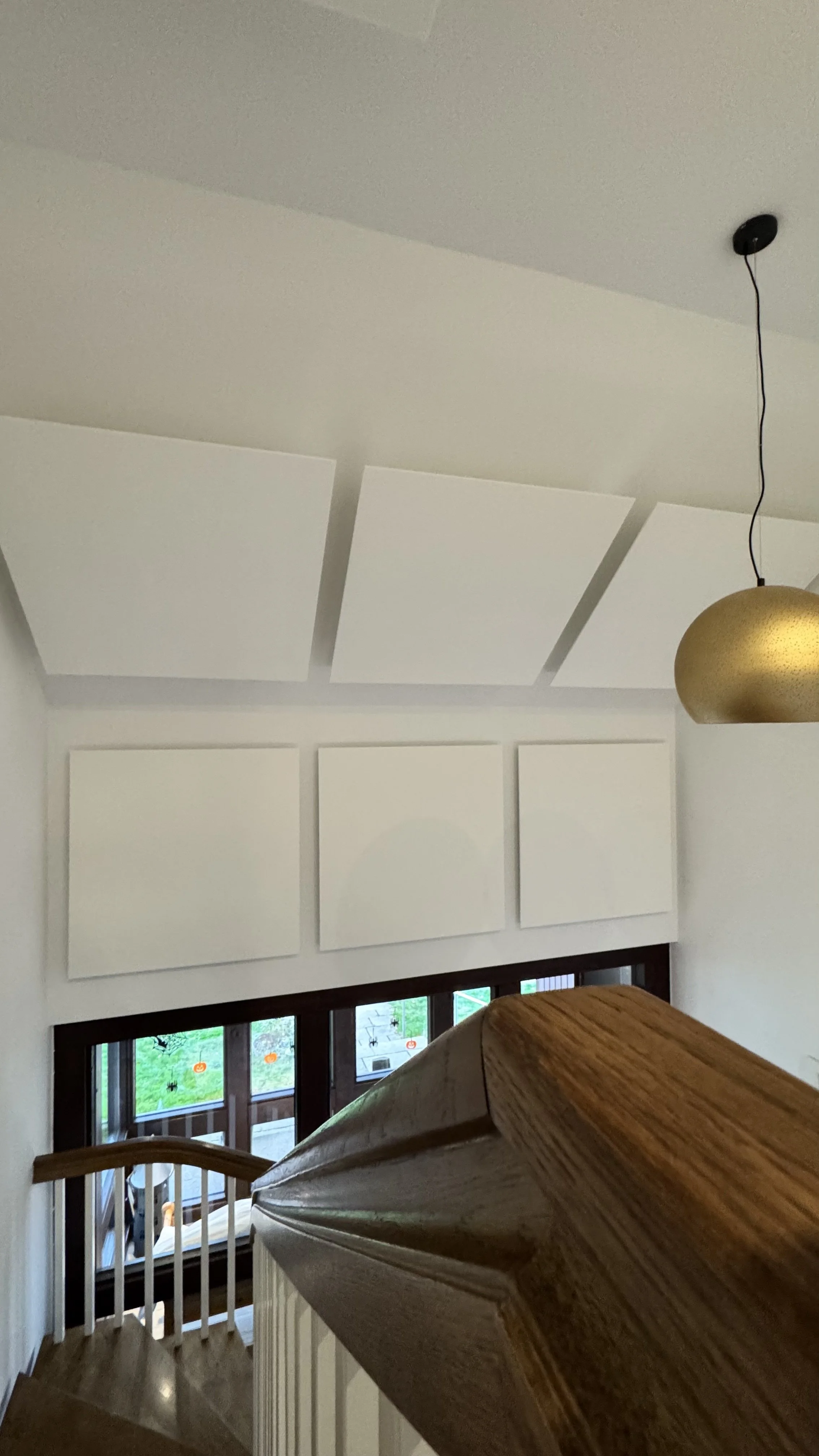 Innenansicht eines Treppenhauses mit weißen Schallplatten an der Wand und einem goldfarbenen Hängeleuchter.