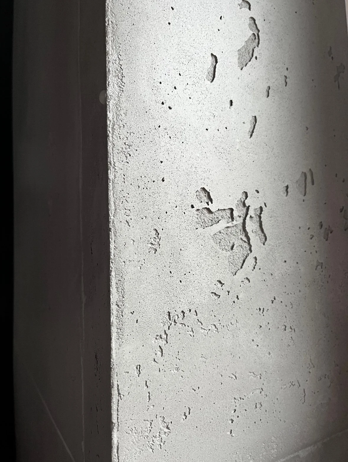 Nahaufnahme einer weißen Wand mit Rissen und Putzverlust.