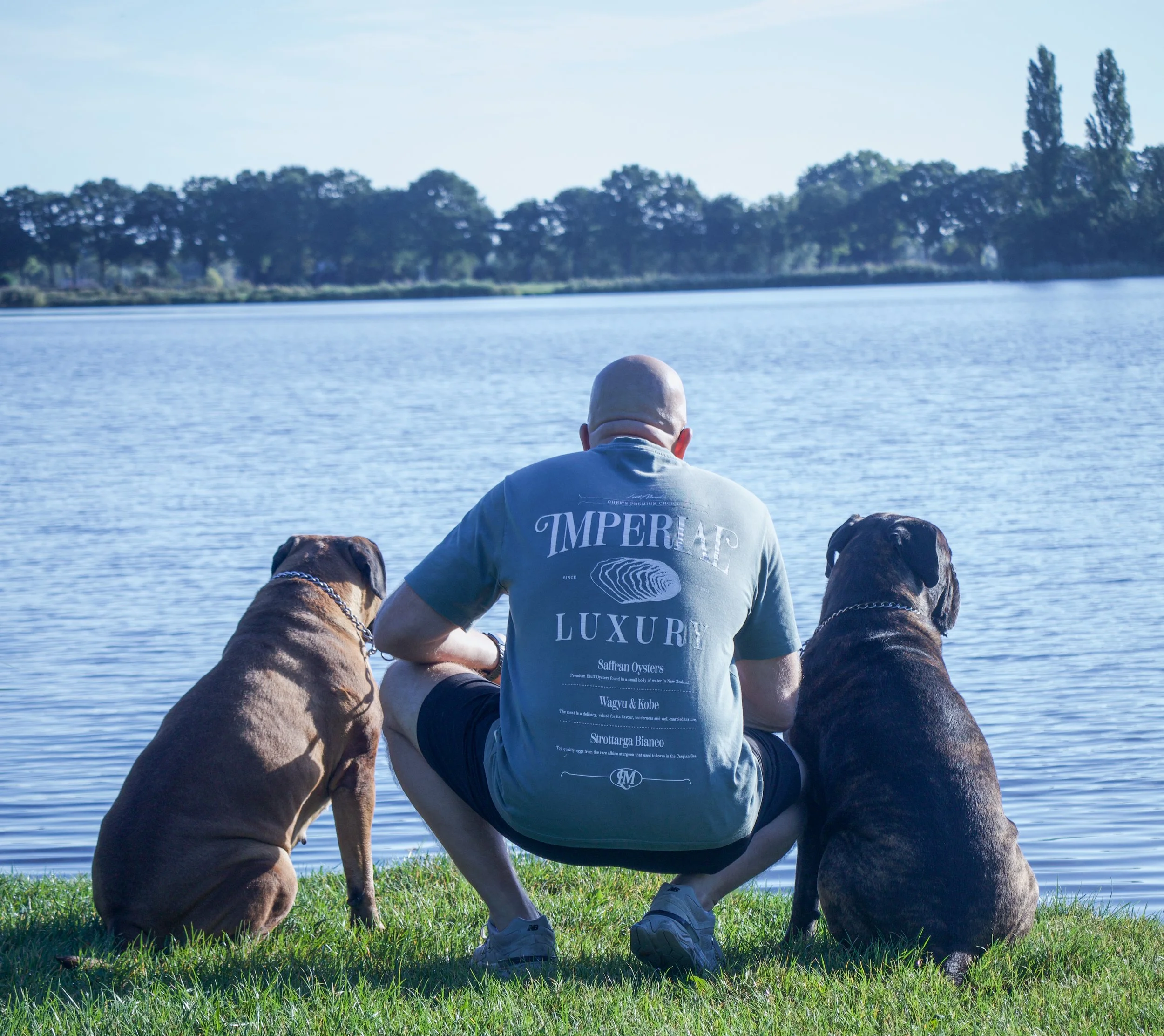 Robert-Jan Emaus zit met zijn twee honden aan de oever van de Weide aa