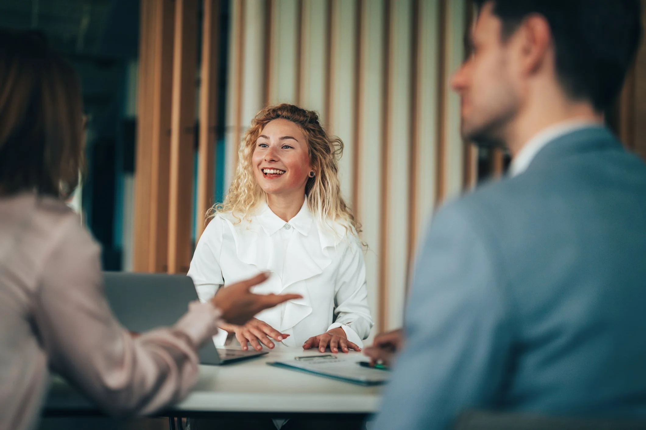En gruppe mennesker som er i et møte, med en kvinne som smiler.