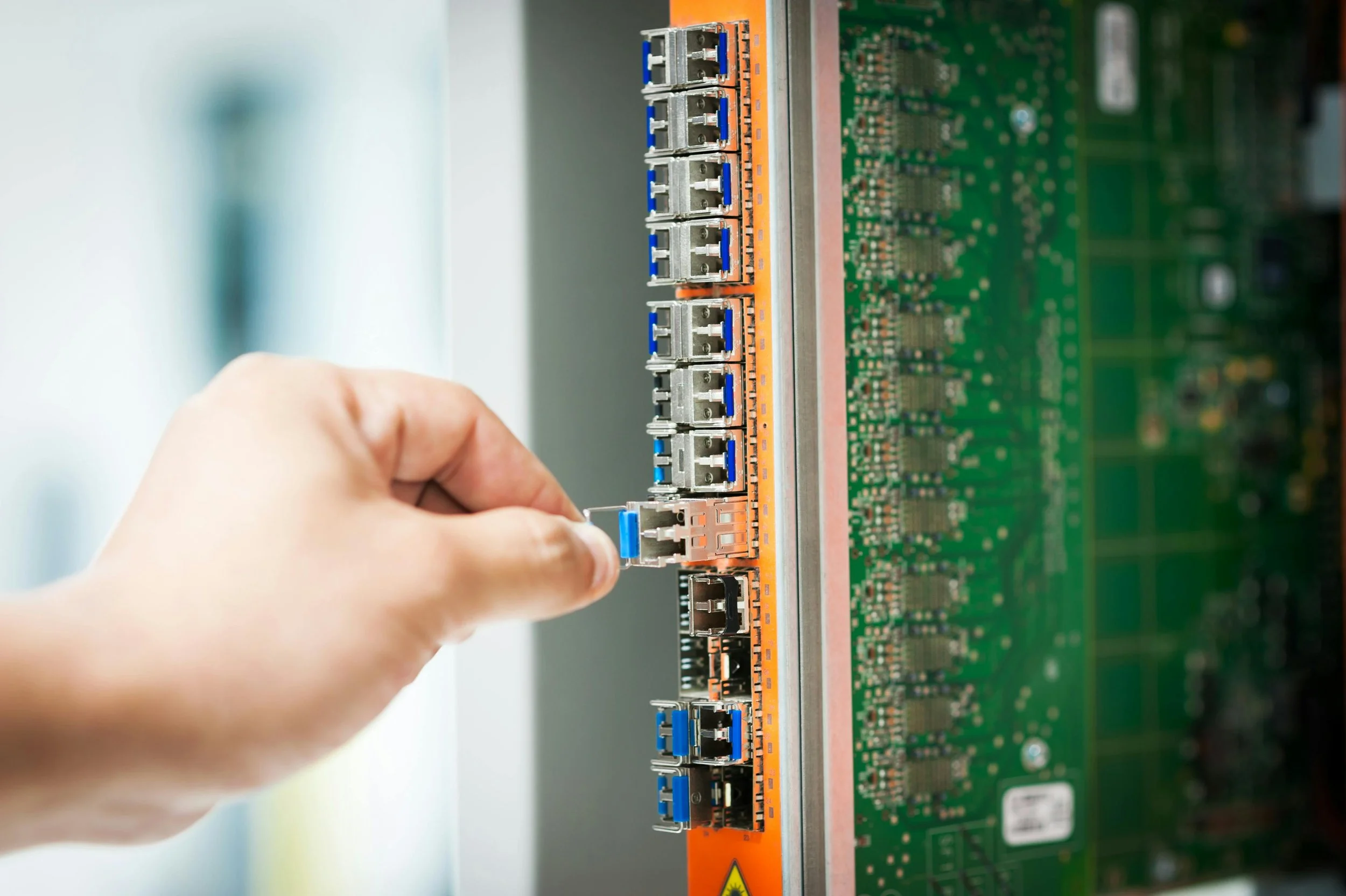 A person's hand adjusting a row of USB ports on a green circuit board in an electronic device.