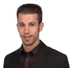 Professional headshot of President and CEO, Jordan Dice wearing a black blazer and dark shirt, smiling slightly against a white background.