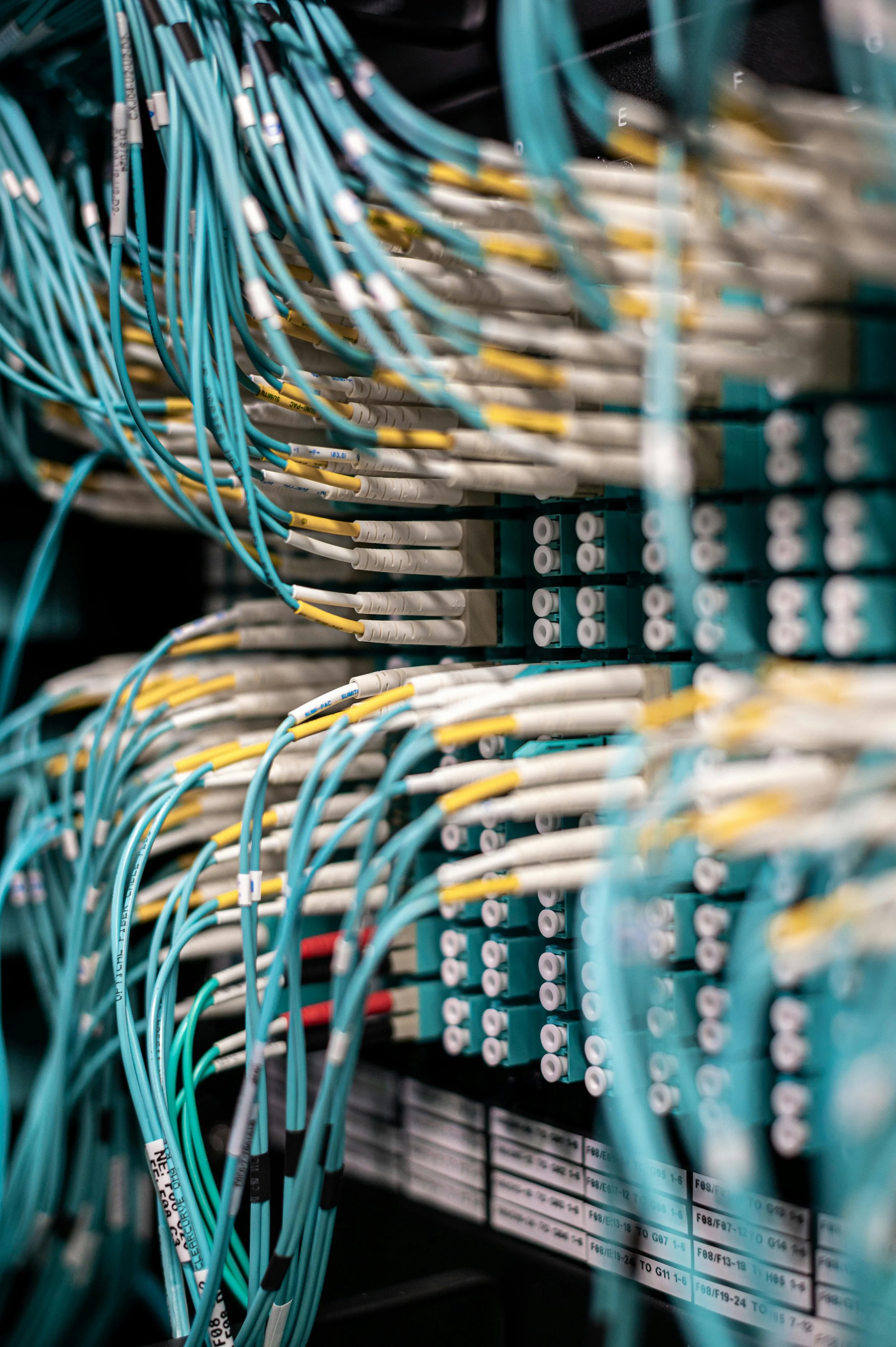 A close-up view of a network server rack with organized blue, yellow, and white network cables connected to patch panels.