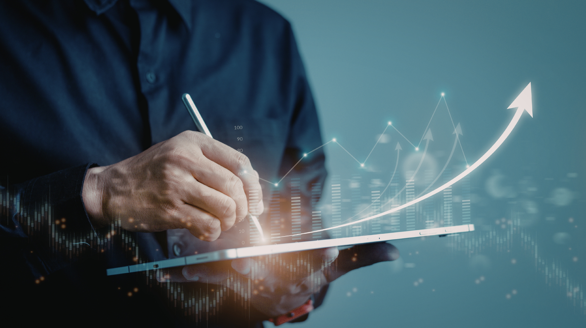 Close-up of a person in a dark shirt drawing an upward-trending graph and arrows on a digital tablet, symbolizing growth and data analysis.
