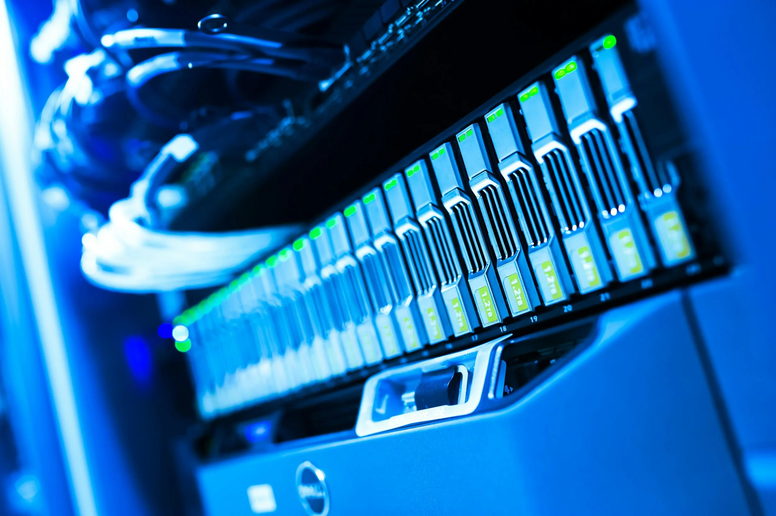 Close-up of a server rack with green and white indicator lights, blue lighting, and network cables connected to the top.