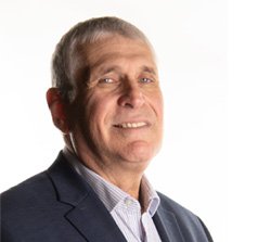 Professional headshot of Executive Vice President, Avi Lupo wearing a dark suit jacket and a light-colored shirt, smiling at the camera.