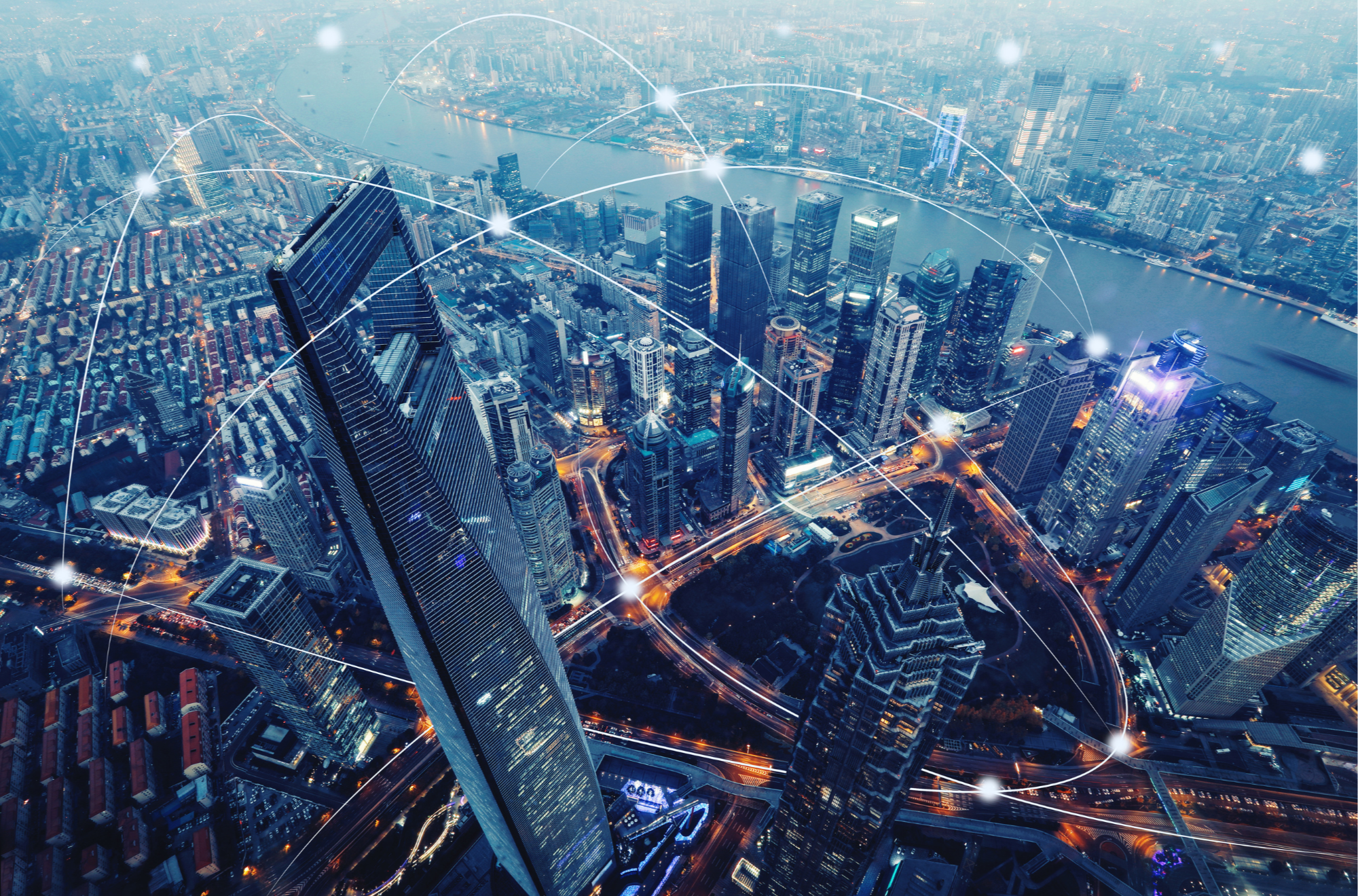 Aerial view of a cityscape at dusk with illuminated skyscrapers and a river, with digital lines and bright spots overlaying the scene, symbolizing connectivity and communication.