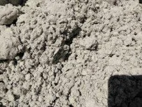 Close-up of light gray sandy or dusty ground with a small shadow in the bottom right corner.