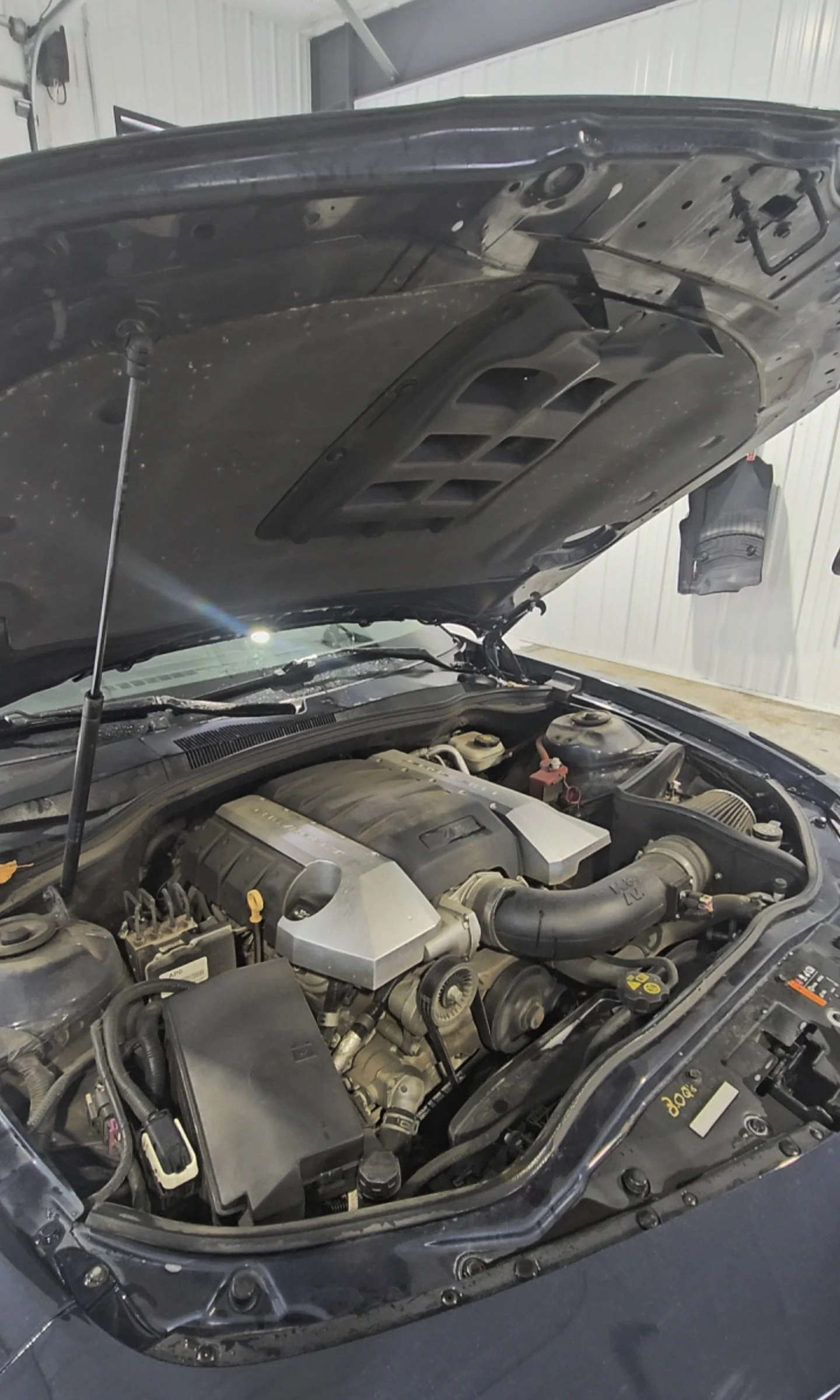Open hood of a car revealing the engine bay with various mechanical parts and components.