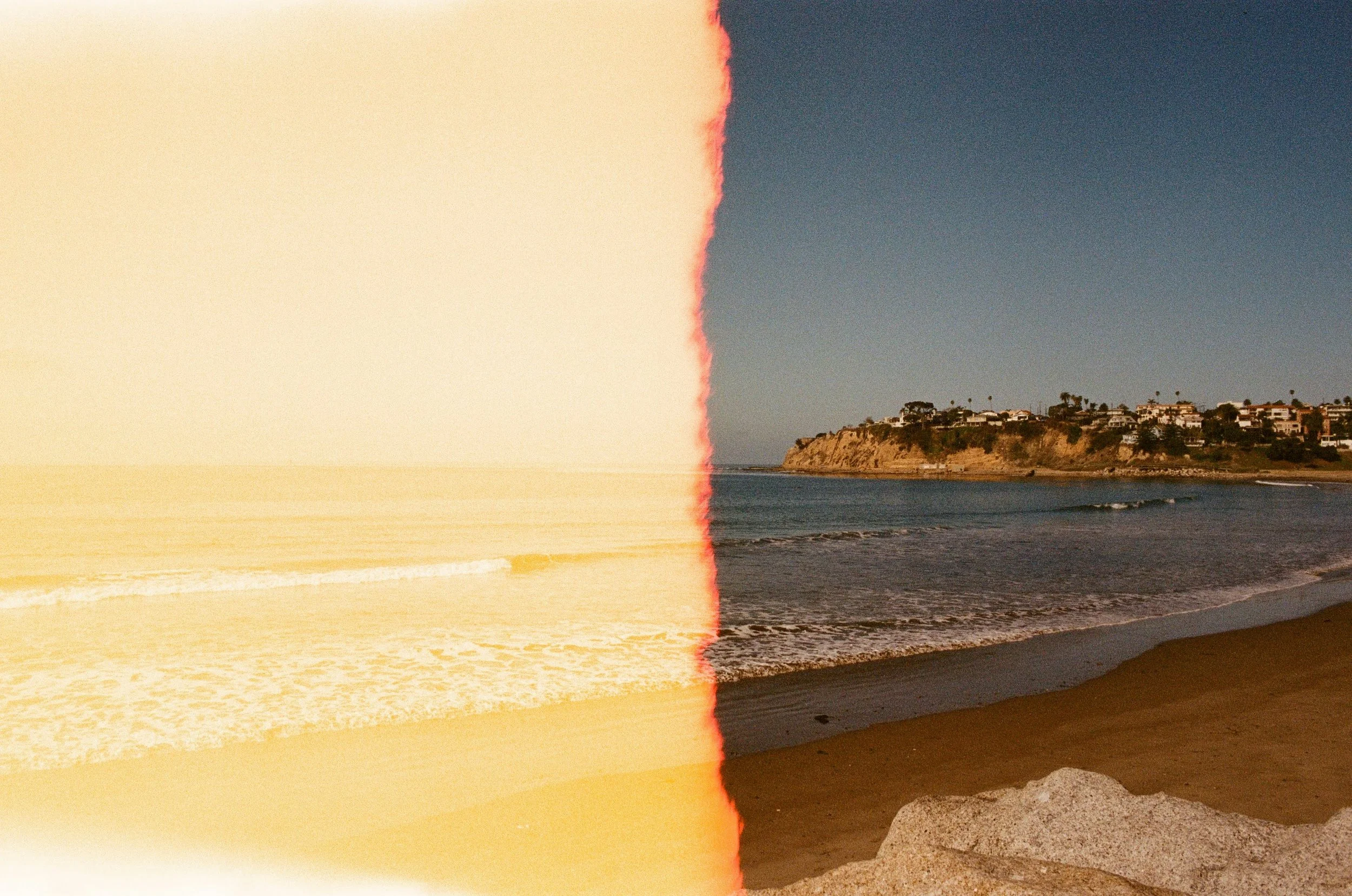 A split image of a beach; the left side appears washed out or overexposed, while the right side shows a clear view of a sandy beach, ocean waves, and a distant residential area on a cliff.