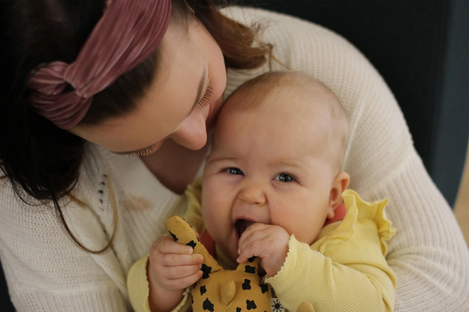 Nainen pussaa vauvaa päähän.