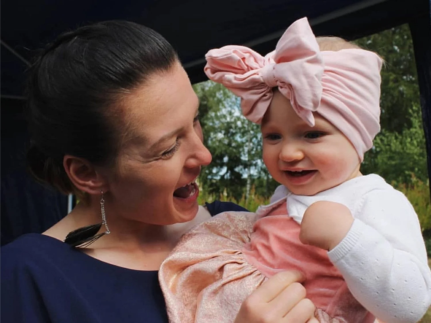 Lastenhoitaja naureskelee pienen lapsen kanssa pitäen tätä sylissä.