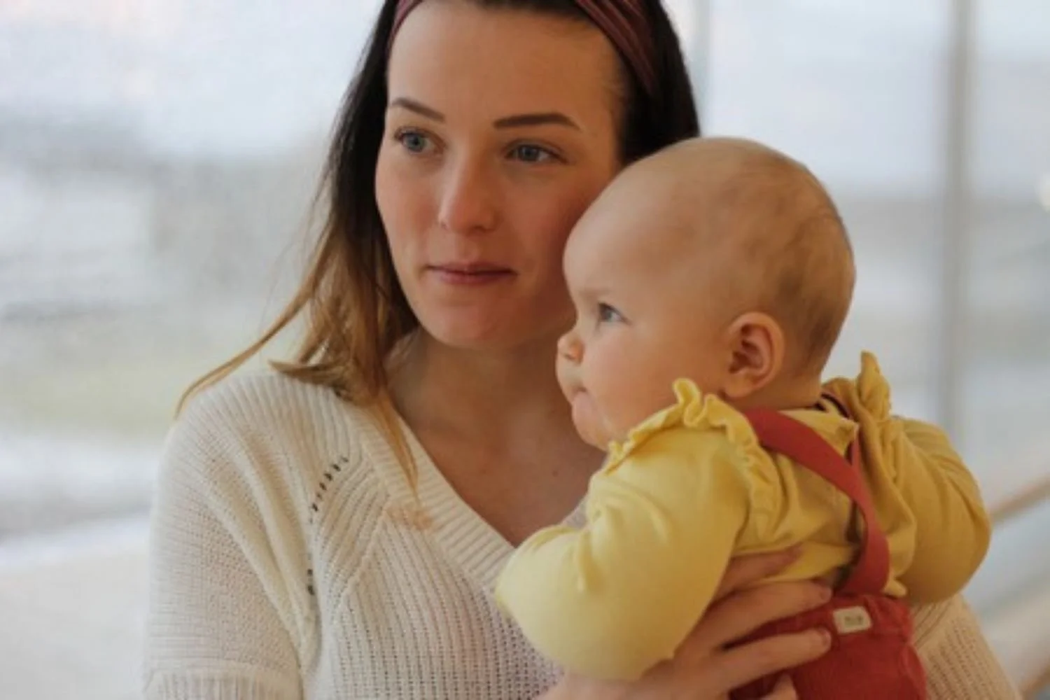 Lastenhoitaja pitää vauvaa sylissä.