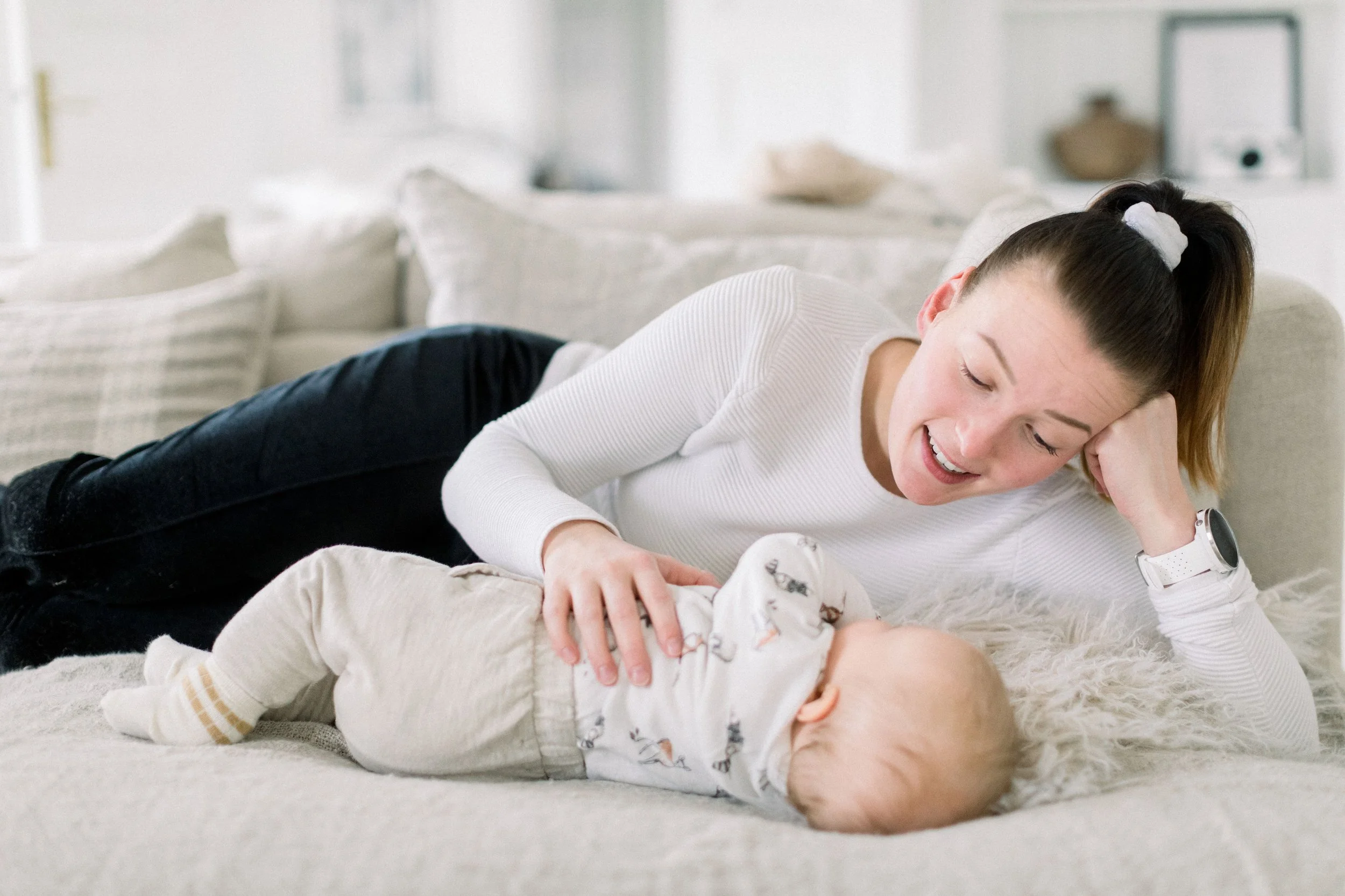 Nainen leikkii vauvan kanssa sohvalla.