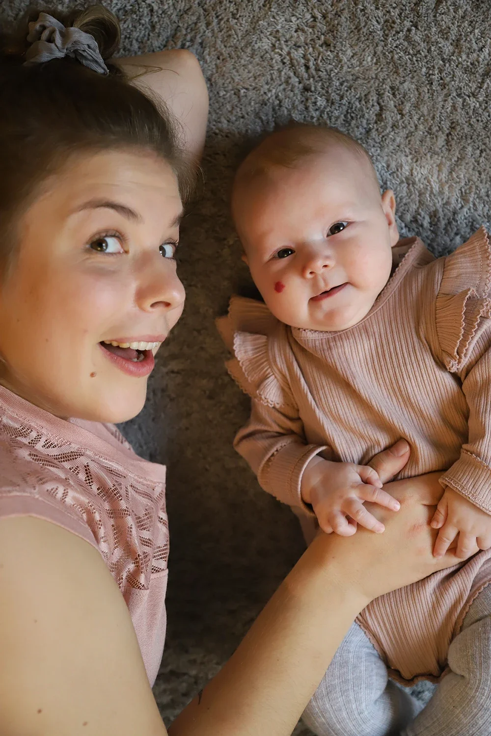 Lastenhoitaja ja vauva makaavat lautalla, vauva katsoo kameraan ja nainen hymyilee.